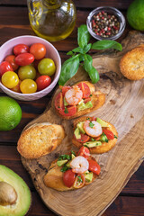 Fototapeta na wymiar Homemade bruschetta with shrimps, avocado and cherry tomato