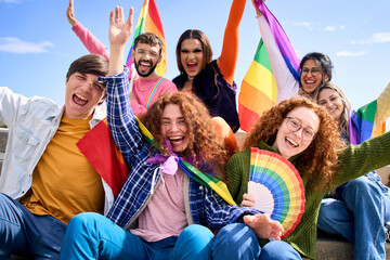 Different excited young friends group celebrating gay pride festival day together. Joyful people LGBT community pose funny looking at camera outdoors. Lesbian, gay, transgender  - obrazy, fototapety, plakaty