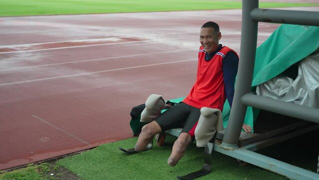 Paralympic Athlete Resting: A determined paralympic athlete, using prosthetic legs, sits by the track during a break in competition, showcasing resilience and the spirit of sportsmanship.