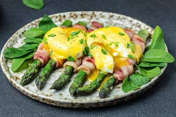 poached eggs benedict with green asparagus wrapped in grilled bacon, Ketogenic diet. Low carb high fat breakfast. Healthy food concept. place for text, top view