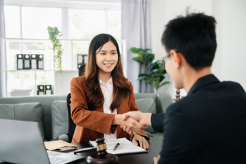 Woman lawyer hand and women client shaking hand collaborate on working agreements with contract documents at the modern office..