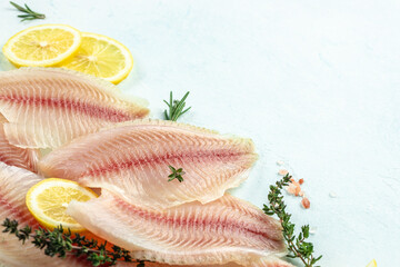 healthy tilapia fish fillets with lemon on a light background. banner, menu, recipe place for text, top view