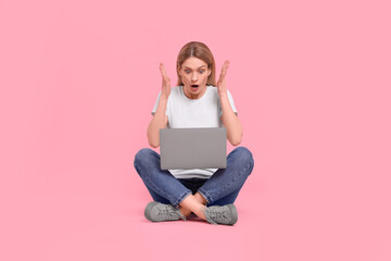 Obraz na płótnie Canvas Emotional woman with laptop on pink background
