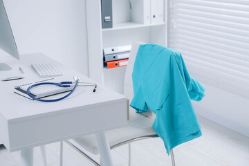 Turquoise medical uniform hanging on chair in clinic