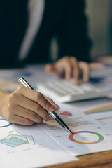 Close-up of a businessman holding a pen pointing to graphs, graphs in corporate financial marketing documents, research, development, management planning, strategy, analysis.