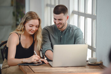 Girl and young man with casual lifestyle working on laptop computer in her studio. Two Caucasian Couples Sitting Outside Workplace