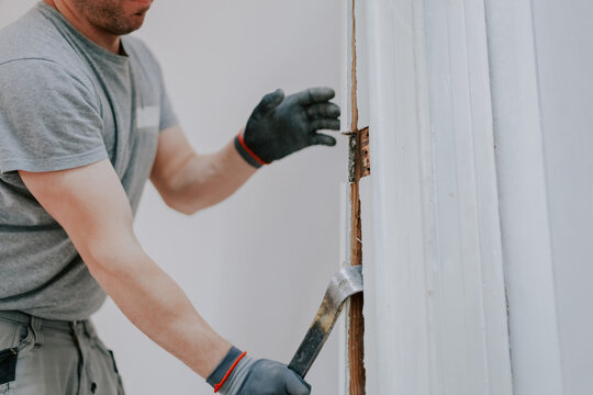 Hands of a man working with a crowbar indoors.