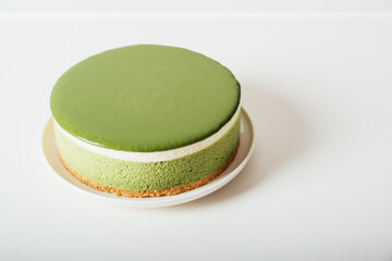 Layered matcha cheesecake on white plate. Gluten free no bake dessert with negative space for text. Healthy sweet food.