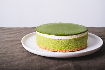 Layered matcha ice cream cheesecake on white plate. Gluten free no bake dessert on neutral background. Healthy sweet food.