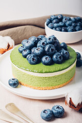 Layered ice cream matcha cheesecake with fresh blueberries. Gluten free no bake summer dessert. Healthy sweet food.