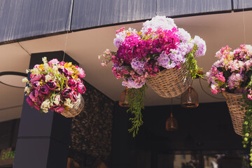 Decorative flowers hanging in basket . Entrance to flower shop or hotel