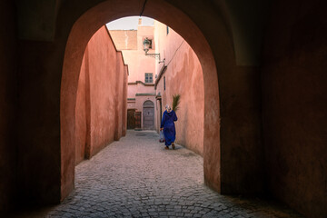 Women walking with flowers in an alley inside the Marrakech Medina