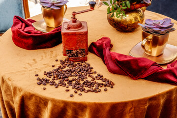 coffee beans with an old grinder and coffee cups on the table