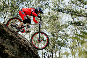 female racer cyclist riding steep descent downhill race in forest, summer mountainbike championship