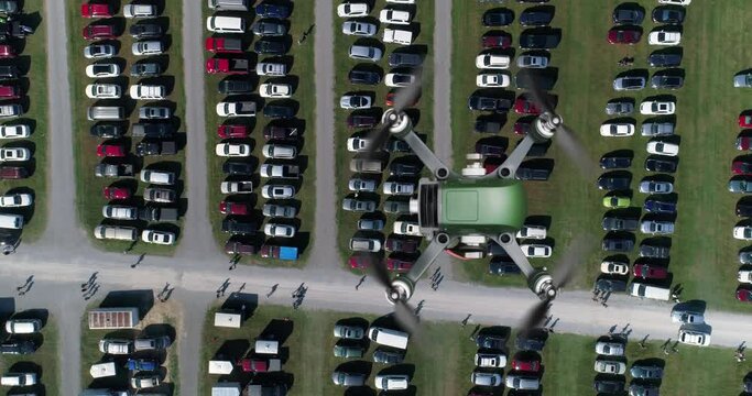 A top-down bird's eye view of a drone flying over a parking lot.	
