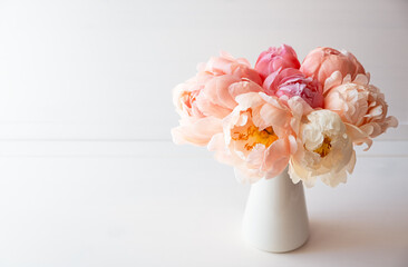 Beautiful bouquet of fresh coral peony flowers in full bloom in vase. Floral still life with blooming peonies. Negative space for text. © Iryna
