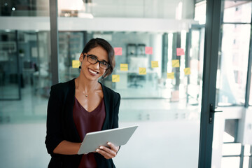 Welcome to the digital age. Cropped portrait of an attractive young businesswoman standing alone in her office and working on a tablet.