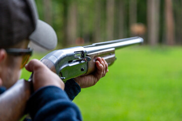 Skeet Shooting .Man shooting at target on an outdoor shooting range at sunny day, training alone,...