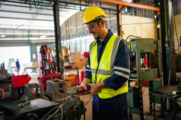 Male technician programs a robot arm with a digital tablet and assembly robot in a factory. Apprentice engineers programming robots in factory.