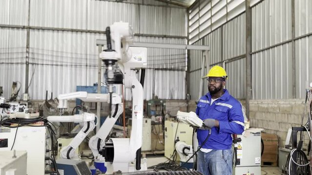 Robotic Arm engineer check on equipment in its with software of an Artificial Intelligence Computer Processor Unit.. Industrial factory employee working in metal manufacturing industry