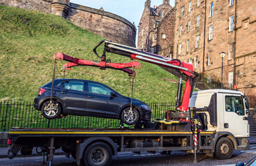 Tow truck lifted illegaly parked car on Johnston Terrace street in historic part of Edinburgh city,...