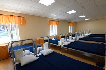 Room of barrack for soldiers well-made beds, nightstands, benches and TV set on the wall. Staroe, Ukraine