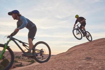 Besides the joyous aspect of it, it is good exercise. Full length shot of two men out mountain biking together during the day.