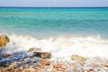 scenery of rock or coastline and white bubbles, ripple wave of turquoise color sea in sunshine day...