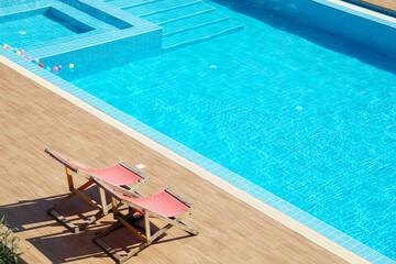 Two red beach chair side swimming pool in sunshine day. Summer activities.