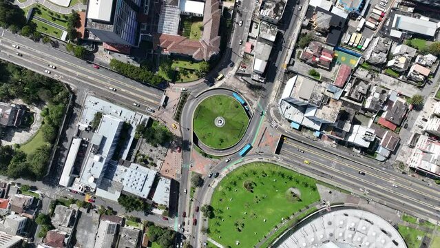 Cars driving through traffic circle in city in South America. Aerial top down drone view of traffic in large intersection in Quito, Ecuador.