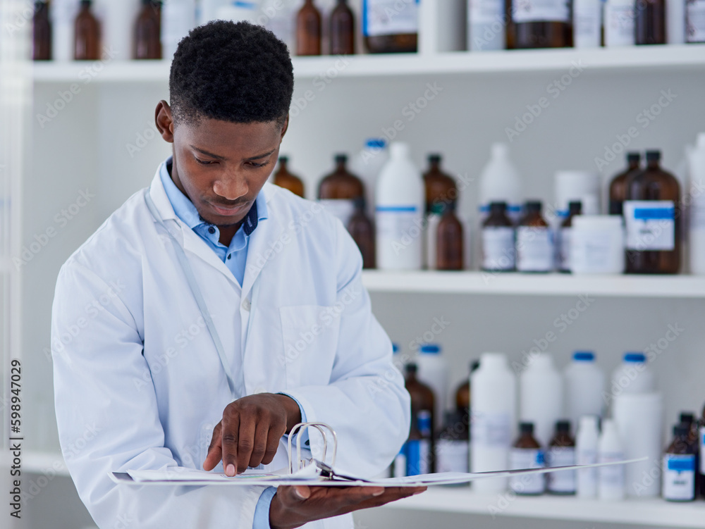 Poster just making sure we have enough stock. a focused young male scientist reading through a notebook ins