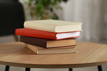 Stack of different hardcover books on wooden table indoors