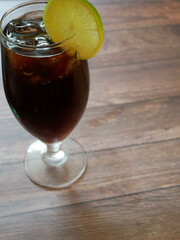 A cocktail of Cuba libra of rum cola and lime in a tall glass in a bar setting