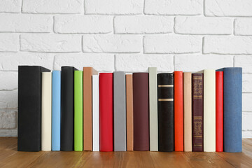 Books on wooden table near white brick wall