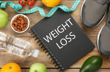 Notebook with phrase Weight Loss Program, sneakers and different products on wooden table, flat lay