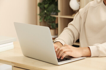 African American man typing on laptop at wooden table indoors, closeup