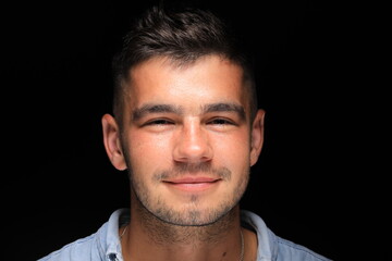 Obraz premium close-up portrait of a handsome man smiling on a black background. a man of model appearance.