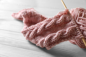 Fototapeta na wymiar Soft pink yarn, knitting and needle on white wooden table, closeup