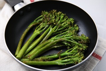 Frying pan with tasty cooked broccolini on table, closeup