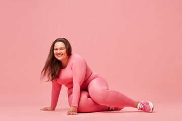 Obraz na płótnie Canvas Self-care and well being. Young overweight woman training in sportswear against pink studio background. Happiness. Concept of sport, body-positivity, weight loss, body and health care