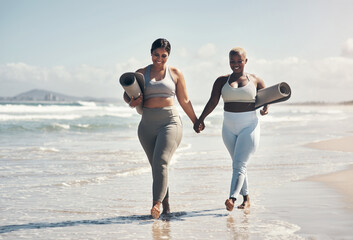 We dont catch up over coffee, we catch up over yoga. two young women walking on the beach with their yoga mats.