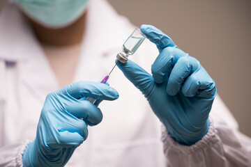 Doctor hand in blue gloves holding influenza vaccine for prevention human.Concept fight against human papilloma virus, nurse in laboratory holding a syringe with HPV vaccines for girl and woman.