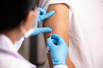 Fototapeta Doctor hand in blue gloves holding influenza vaccine for prevention human.Nurse holding syringe make injection in shoulder of patient in hospital.Covid-19 or coronavirus vaccine. obraz