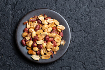 Pile of roasted peanuts on black background, space for text