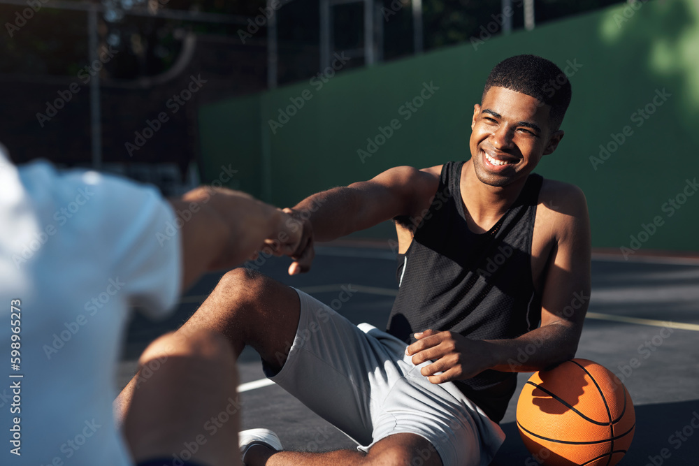 Poster dude, you skills are mad. a sporty young man giving his teammate a fist bump on a basketball court.