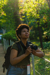 Young black African American female photojournalist with dark curly hair looking up searching for...