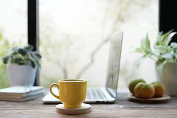 yellow coffee cup and laptop and white flowers on white table indoor work from home