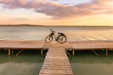 Cycling tours around lake balaton in hungary, setting sun and bicycle standing on wooden embankment...