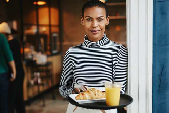 Friendly waitress standing with food in a cafe - Powered by Adobe