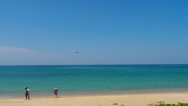 Airplane approaching to land over the blue sea. People taking pictures of an airplane on the beach. Tourism and travel concept Generative AI